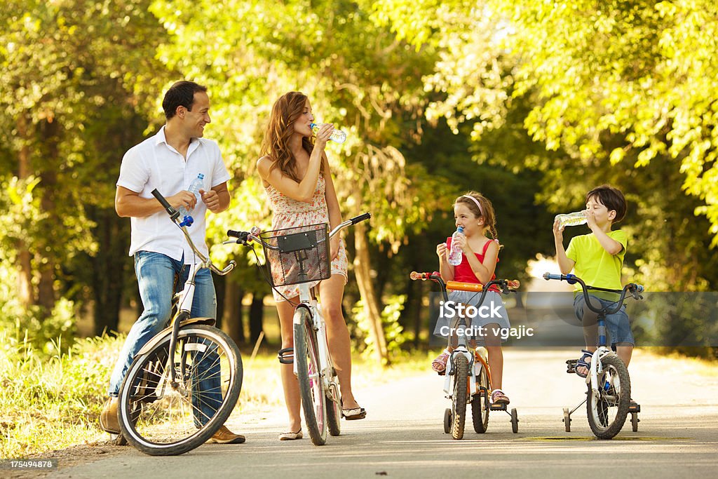 Молодая семья с велосипедами в парке - Стоковые фото Двухколёсный велосипед роялти-фри