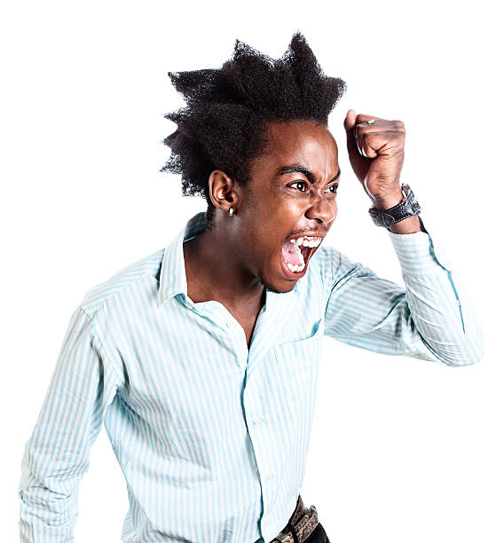 Angry young man yells and raises clenched fist threateningly A young man with a zany afro looks absolutely enraged and frustrated as he snarls and shakes his fist at something or someone. punching one person shaking fist fist stock pictures, royalty-free photos & images