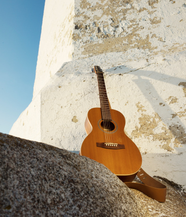 A guitar leans against the historic Peggy's Cove lighthouse in Peggy's Cove Nova Scotia.  Evening light.