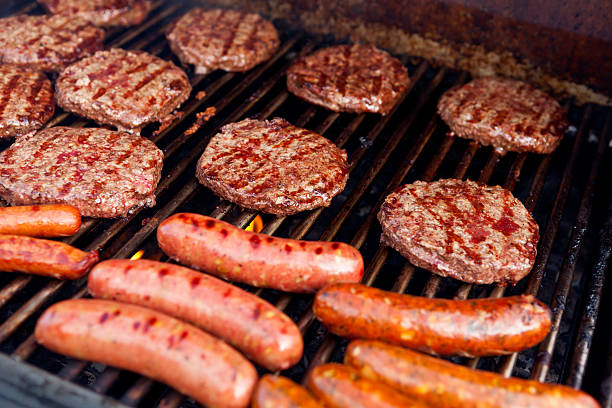 Barbeque Grill with Hamburgers hot dogs and sausage "Hamburger patties, sausages and hot dogs cooking on a outdoor barbeque grill.  The focus is on the hamburgers in the center of the frame." grill burgers stock pictures, royalty-free photos & images