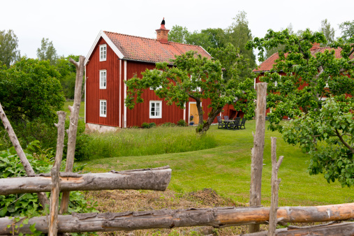 Farm house in souther Sweden behind a traditional roundpole fence. Typical garden furniture on the lawn.Similar images: