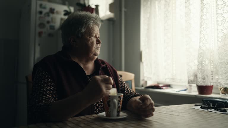 SLO MO Lone Senior Woman Sitting at Table Dipping Teabag into Cup at Home