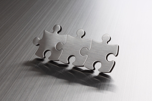Metal puzzle pieces on a #aaBrushed metal