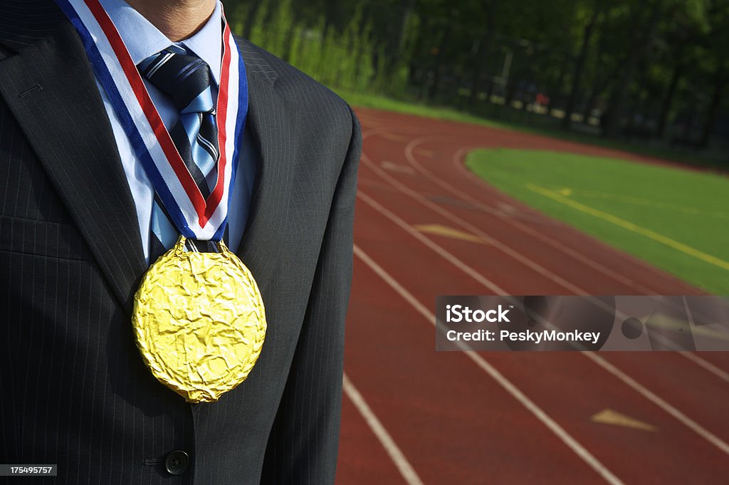 Uomo d'affari sta con Medaglia d'oro all'aperto accanto alla pista da corsa - Foto stock royalty-free di Adulto