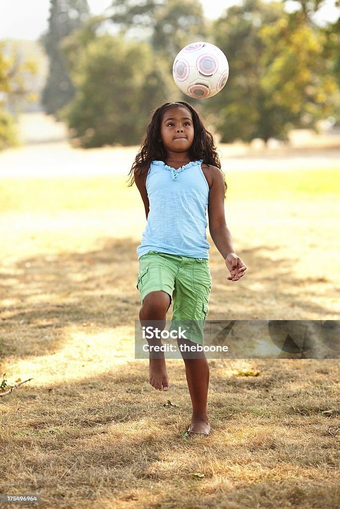 Giovane ragazza etnica giocare a calcio nel parco. - Foto stock royalty-free di Calcio - Sport