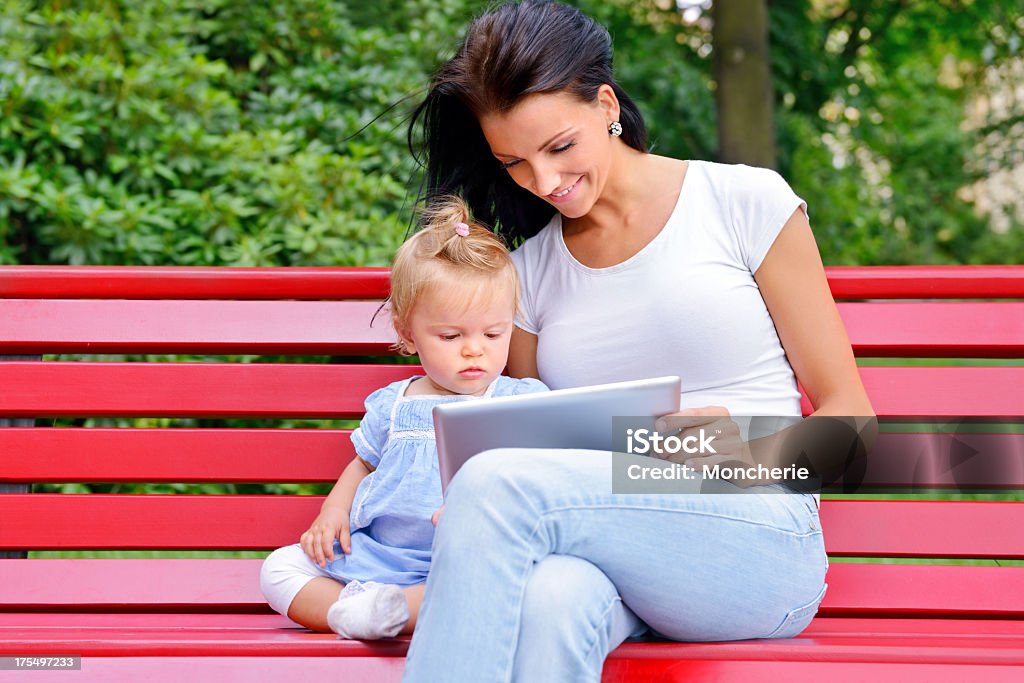 Linda jovem mãe com seu bebê menina usando tablet digital - Foto de stock de 20 Anos royalty-free