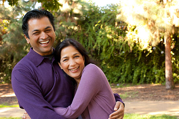 Smiling man and woman, both wearing purple, hugging outside stock photo