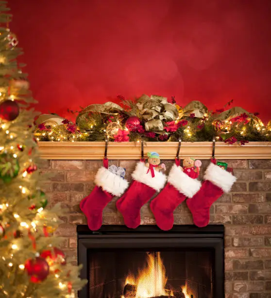 Fireplace decorated with garland and christmas stockings for the holiday season.