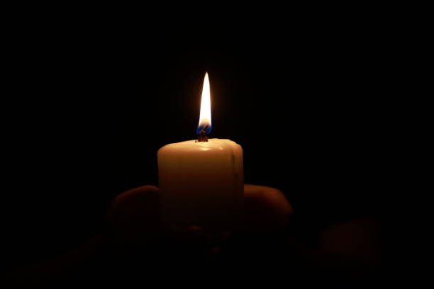 Hands holding a candle over dark background