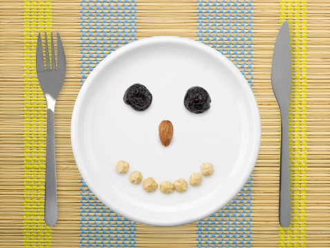 Smiley Face Made By Dried Plum And Nuts In  White Plate