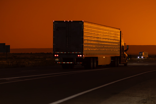 Truck driver transports cargo on a truck against the backdrop of sunset at night. The concept of compliance with the work and rest regime of drivers, tachograph
