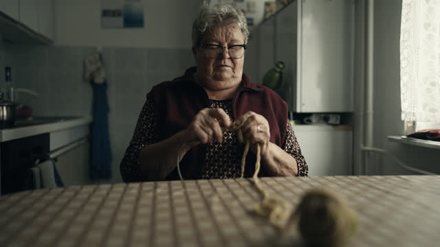 Obese Senior Woman Sitting at Table while Knitting at Home