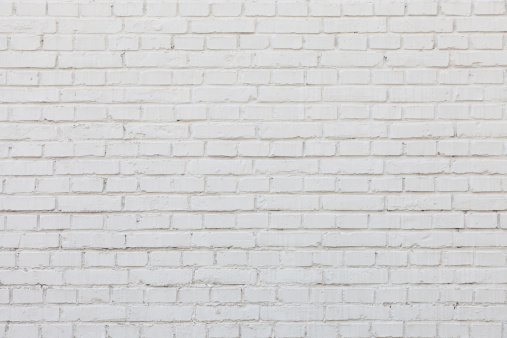 The painted (white) brick wall of the building. White brick wall construction background, rough surface.