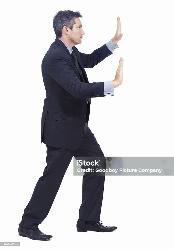 Pushing the boundaries of business Profile of a businessman pushing against an invisible wall - isolated Pushing Stock Photo