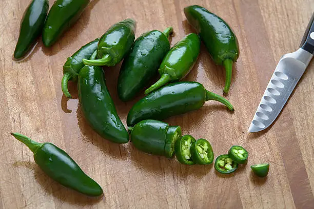 Fresh jalapenos on a cutting board with knife