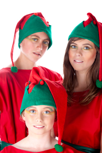 Three children dressed up as Christmas elves. Focus on smallest elf.