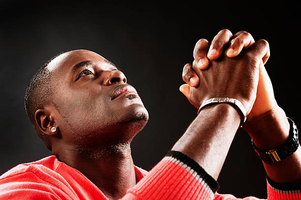 istock Young man looks up, hands clasped, praying fervently 175503827