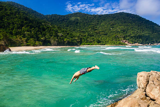 Diving at paradise Young man diving into the ocean. cliff jumping stock pictures, royalty-free photos & images