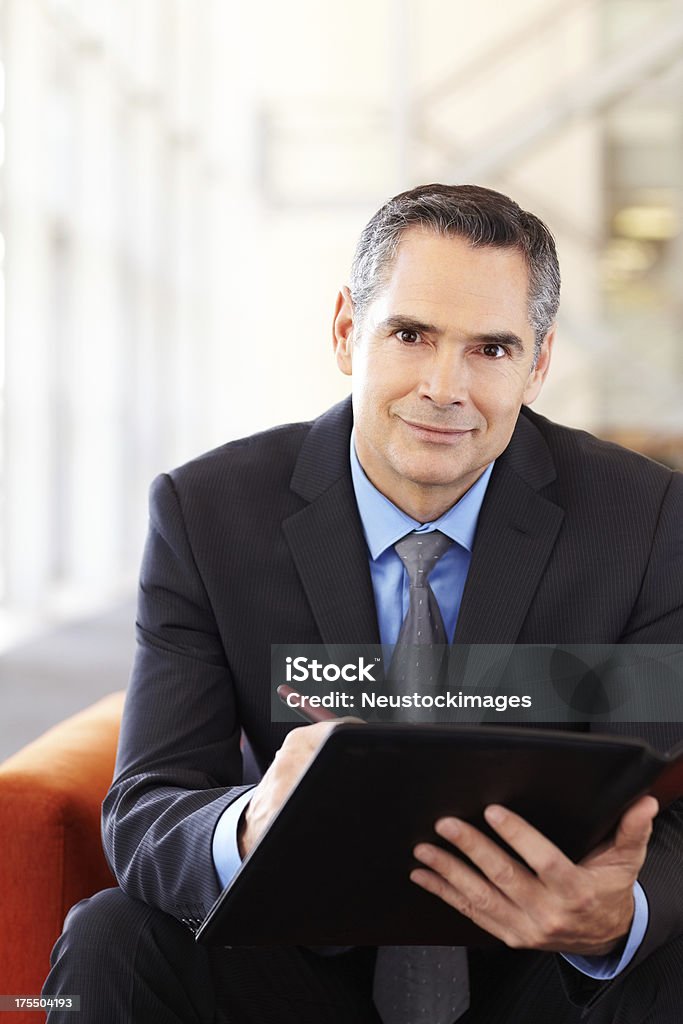 Male Entrepreneur Making Notes Before Meeting Portrait of mature male business entrepreneur making notes before meeting while sitting in office lobby. Vertical shot. Men Stock Photo