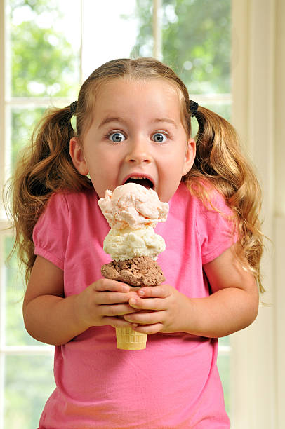 Cute Young Girl Eating a Triple Decker Ice Cream Cone stock photo