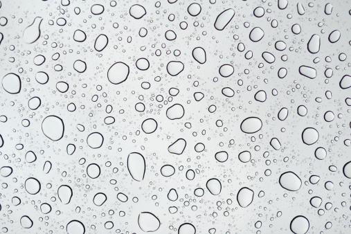 Many rain drops on a surface making an abstract design.