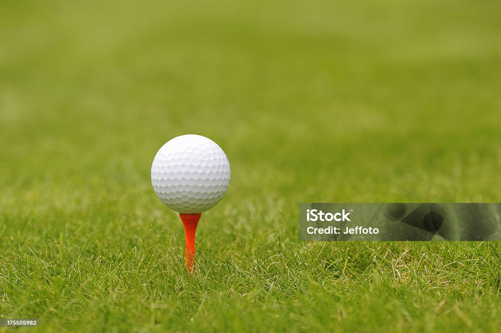 Golf ball on an orange tee peg White golf ball on tee peg with shallow depth of field. Equipment Stock Photo