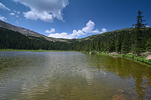 Arapaho National Forest, Colorado - 07/28/2021: Distant hikers on shore of Hassell Lake on sunny summer afternoon.