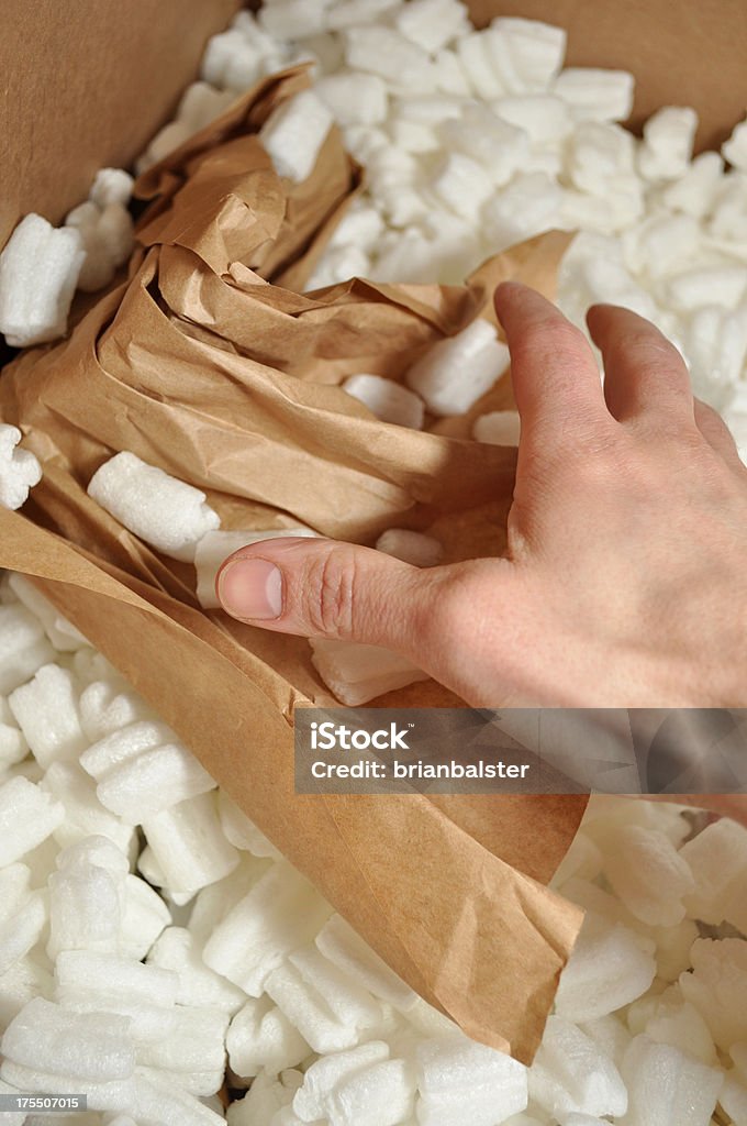 Shipping Products at Warehouse A human hand is shipping products out of an order fulfillment warehouse. The packing peanuts are environmentally responsible and made from biodegradable corn starch.   Also could be a customer or order receiving department unpacking an order. Peanut - Food Stock Photo