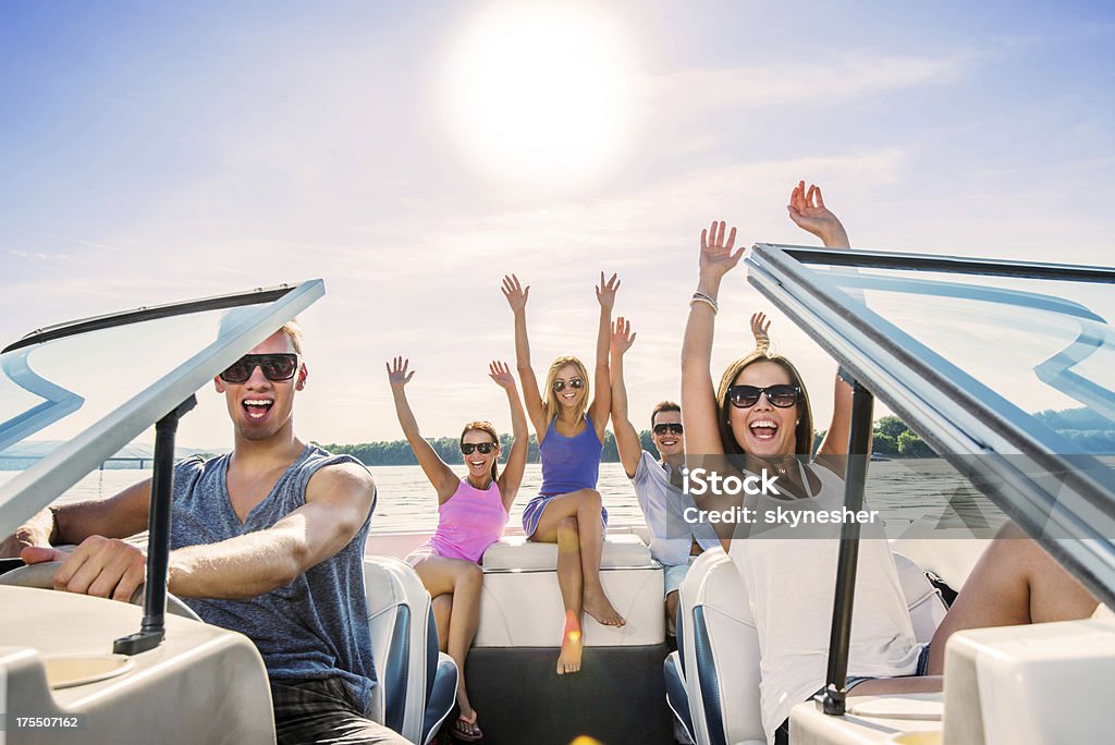 Cheerful group of young people enjoying in speedboat ride. Young ecstatic group of young people sitting in a speedboat and enjoying the ride. Party - Social Event Stock Photo