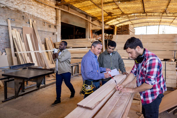 Foreperson discussing a design with a group of carpenters at a wood factory Foreperson discussing a design with a group of Latin American carpenters while working at a wood factory - timber industry concepts lumber industry timber lumberyard industry stock pictures, royalty-free photos & images