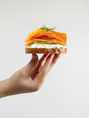 Woman holding salmon sandwich with whole wheat bread.