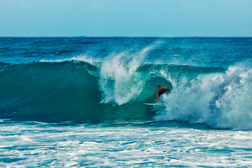 Photo of a Hawaiian surfer riding the barrel of a big blue wave.