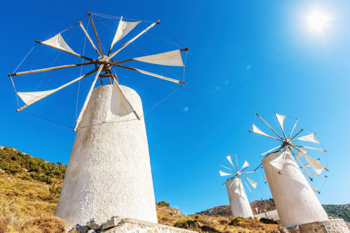 Windmills upon a hill against light blue summer sky.