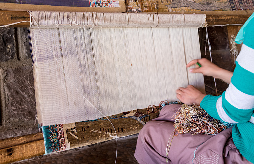 carpet loom, hands of a rustic Turkish woman weaving carpet or rug on loam in Turkey. traditional weaving way in Turkey. turkish handcrafted product by hand