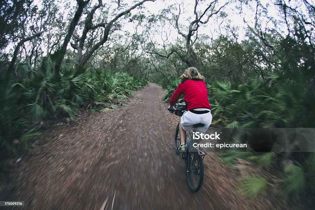 Atletismo masculino en pista de ciclismo en el bosque al atardecer - Foto de stock de Isla de Cumberland libre de derechos
