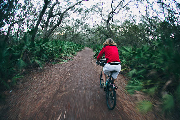 atletica maschile ciclismo su sentiero di bosco al crepuscolo - cumberland island foto e immagini stock