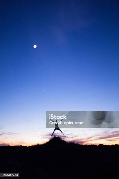 Male Jumping With Arms Outstretched While Running At Sunset Stock Photo - Download Image Now