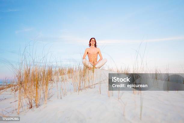 Healthy Man Joven Meditando En La Playa Mientras Se Distiende En La Arena Foto de stock y más banco de imágenes de 20 a 29 años