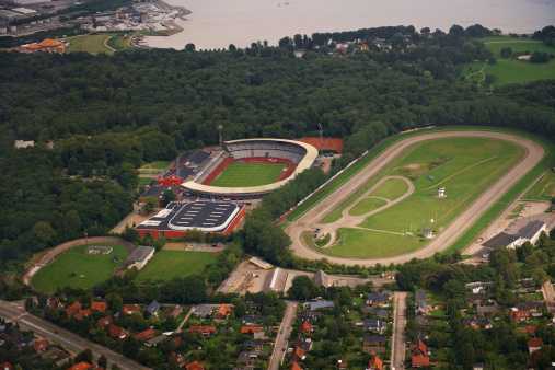 Aerial view of a sports area. Arenas, stadium, horse track, bike track near ocean and harbor.