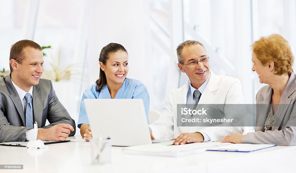 Doctors Collaborating with a Business Team Doctors and a business team work together while sitting around smiling and talking. Manager Stock Photo