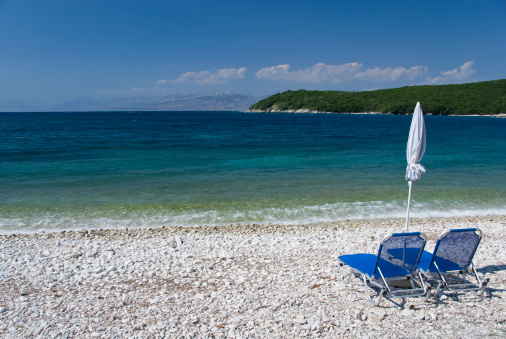 Beach chairs and umbrella on a pebble beach.