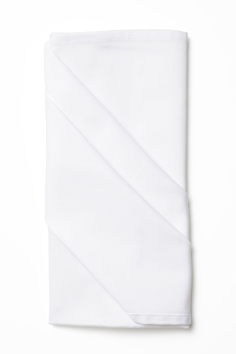 Overhead shot of folded white napkin isolated on white background with shadow.