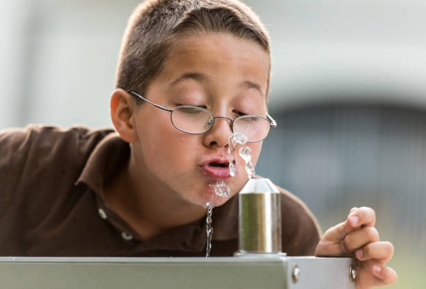 Little boy drinking water Nine years old caucasian child drinking water in a public fountain whites only drinking fountain stock pictures, royalty-free photos & images