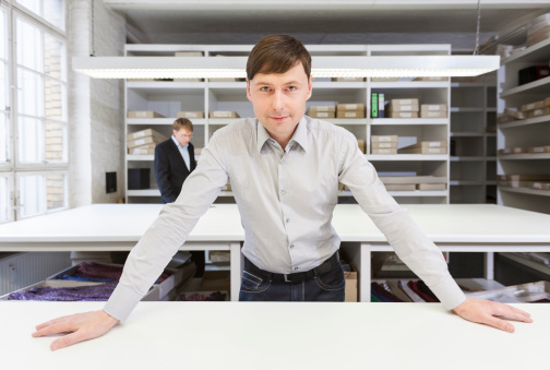 A man confident businessman looks into the camera and is ready to begin his day at a tie factory.