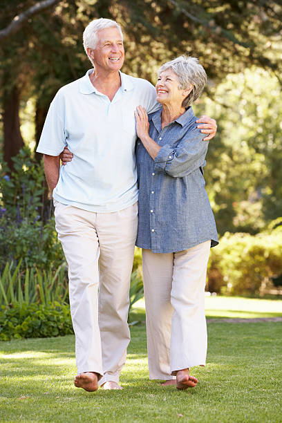starsza para spaceru w ogrodzie w domu - senior couple senior adult walking action zdjęcia i obrazy z banku zdjęć