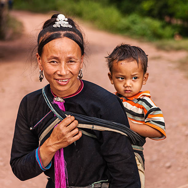 женщина с hill tribe носить ее ребенка - laos hut southeast asia shack стоковые фото и изображения
