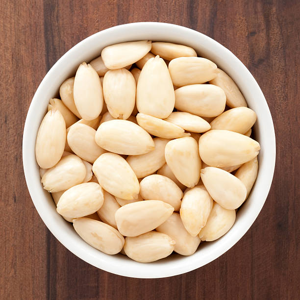 Almonds Top view of white bowl full of peeled almonds peeled stock pictures, royalty-free photos & images