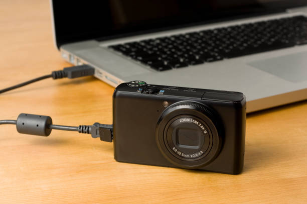 Camera to computer photo and video data transfer Transferring photos from a camera to a laptop via USB cable. point and shoot camera stock pictures, royalty-free photos & images