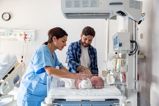 Midwife introducing a happy father to his newborn baby while she is in the incubator
