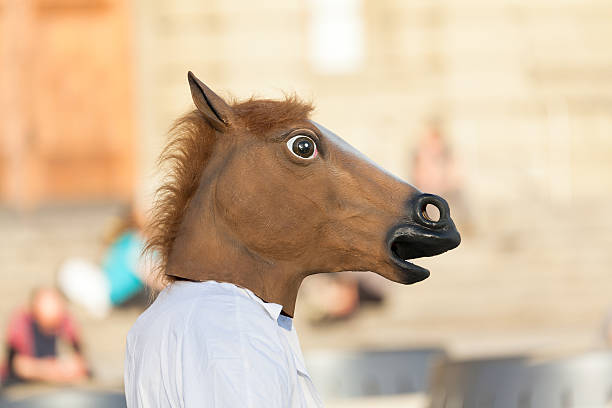 Man wearing the head of a horse in blurred background stock photo